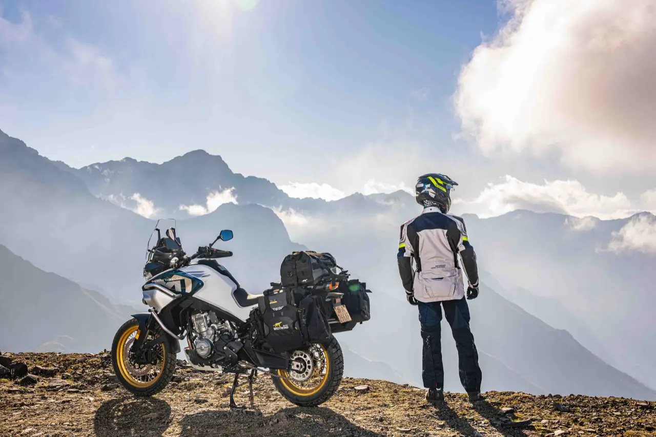 Motorista junto a su moto trail contemplando un paisaje de montaña